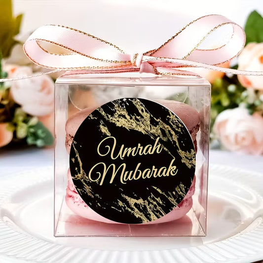 Gift box with 'Umrah Mubarak' sticker label and pink ribbon on a floral background