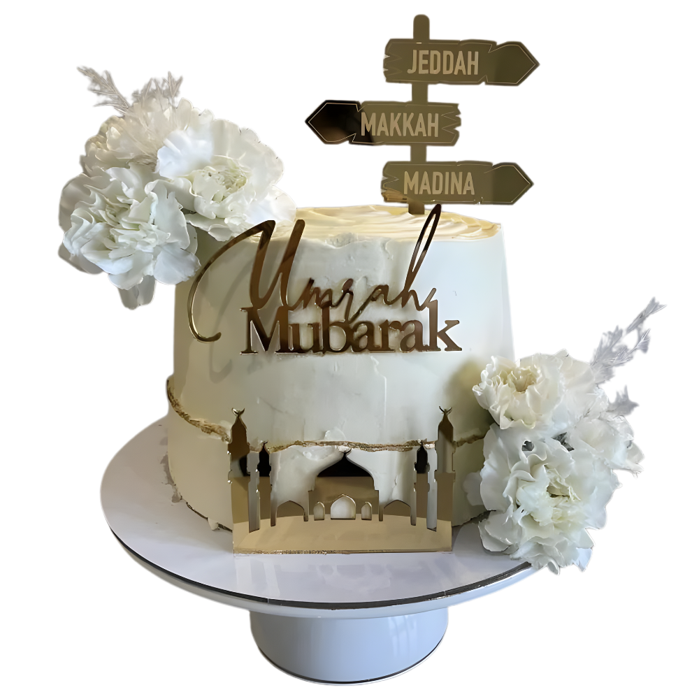 Decorative cake with 'Umrah Mubarak' text and floral elements on a white background