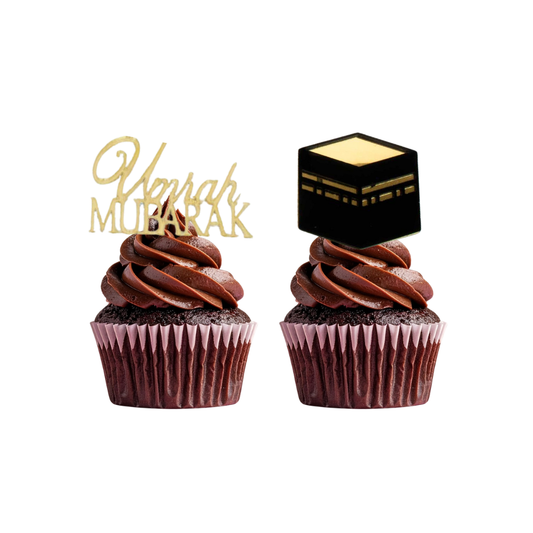 Two chocolate cupcakes with 'Umrah Mubarak' text and a kaaba model on a white background