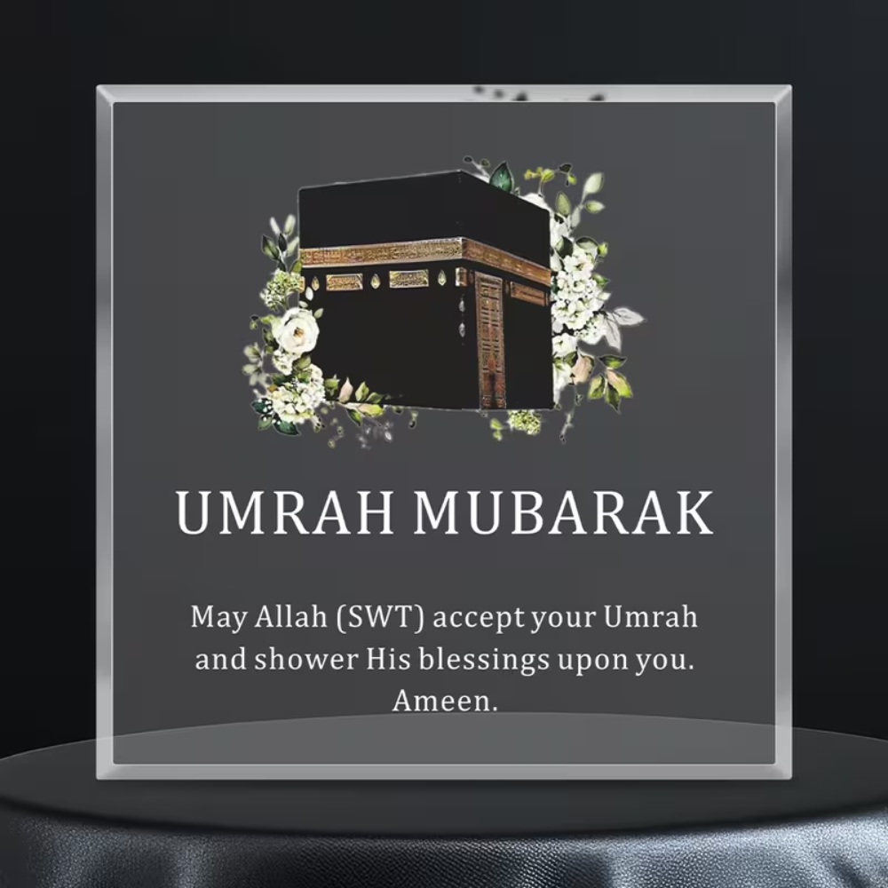 Decorative plaque with Kaaba illustration and 'Umrah Mubarak' text on a dark background